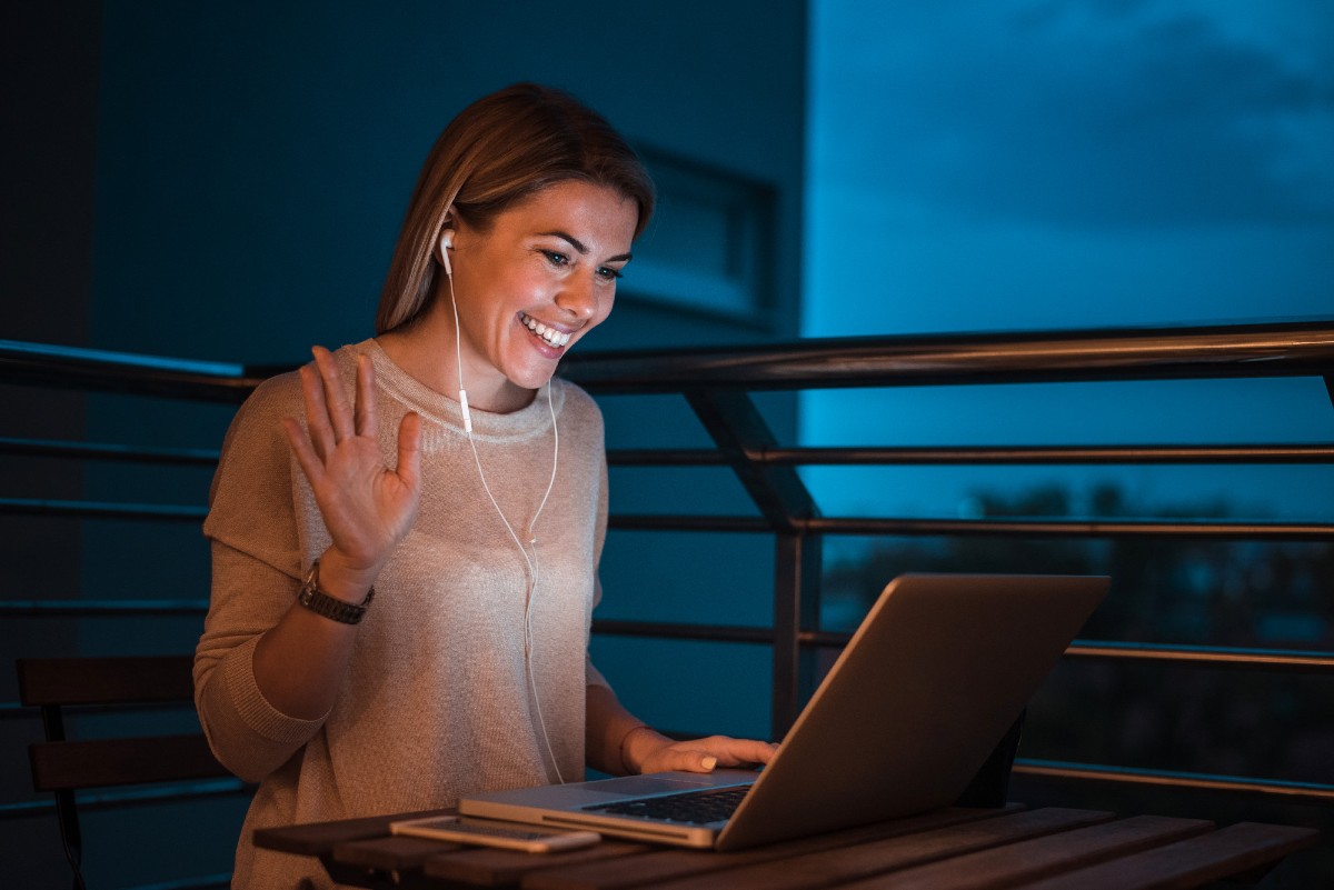 Young smiling woman having a video call using laptop at night